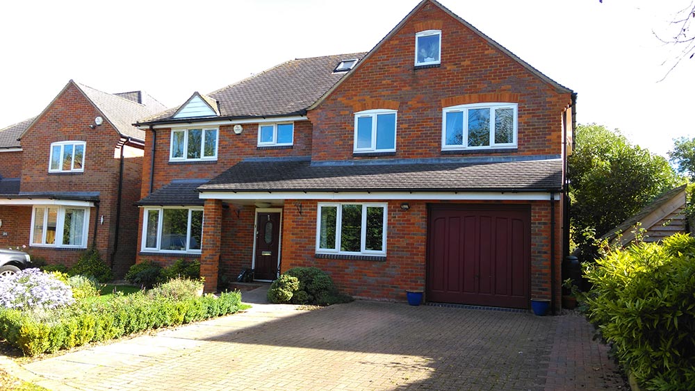 Two-story brick residential house with garage, showcasing AMBS Eco Solutions' home improvement and maintenance expertise.