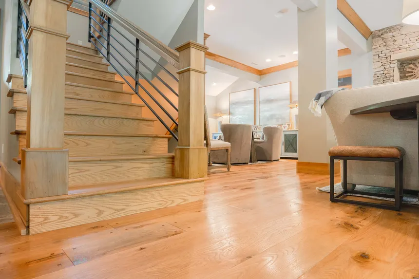 Wooden staircase in a modern interior showcasing AMBS Eco Solutions' flooring service quality and cozy seating area.